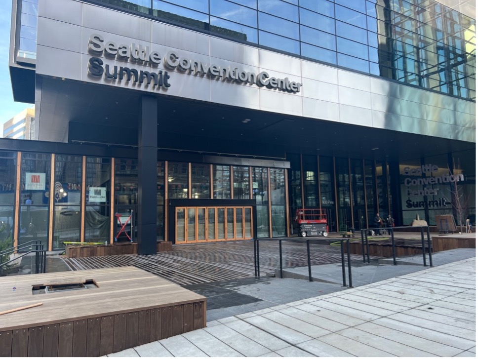 a photo taken at the main entry of the Summit building. The photo shows a ramp with a railing on the left and a few stairs on the right with railing. The entrance is to the far right of the photo.