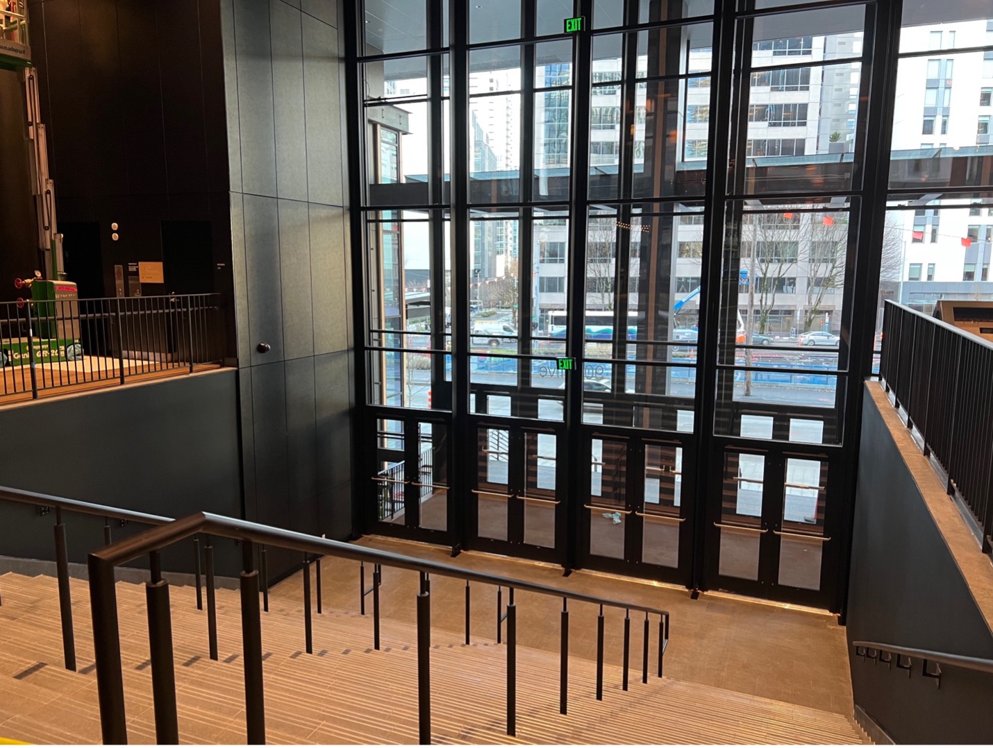 This photo was taken at the top of the set of stairs of the Olive Avenue entrance. The photo shows the main bank of doors and the stairs leading up to Summit Lobby. On the left of the stairs, there is a platform where the accessible lift lets out