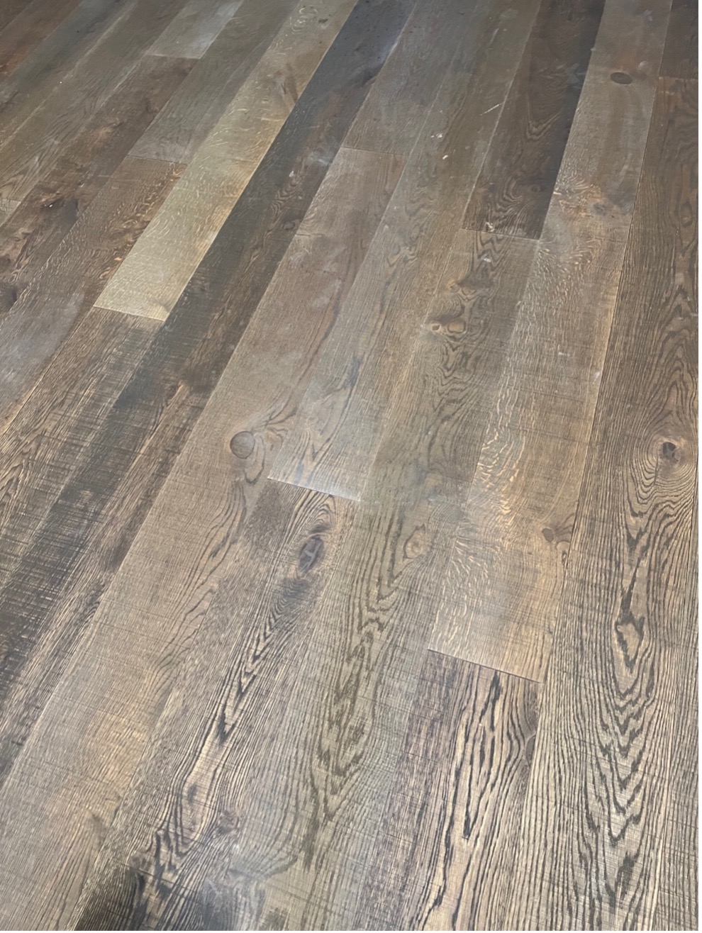 This photo shows a close-up of the flooring in Summit hallway. It is light gray-brown hardwood panels, with visible grain.