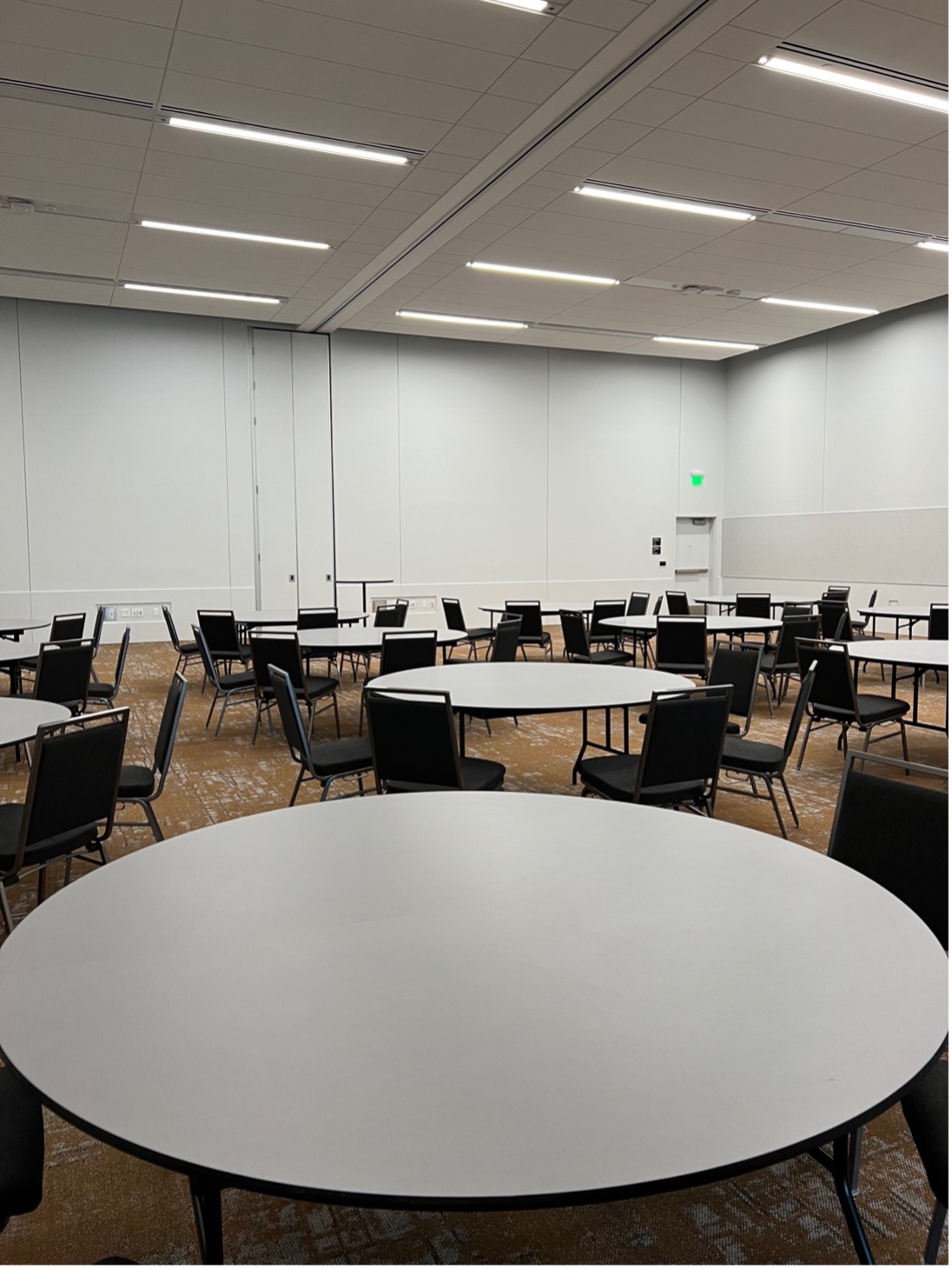 A photo of a meeting room set with table rounds and black chairs.