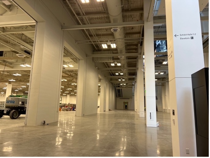 This photo shows a large concrete area with white columns. To the left are large, wide openings to the Bookfair.