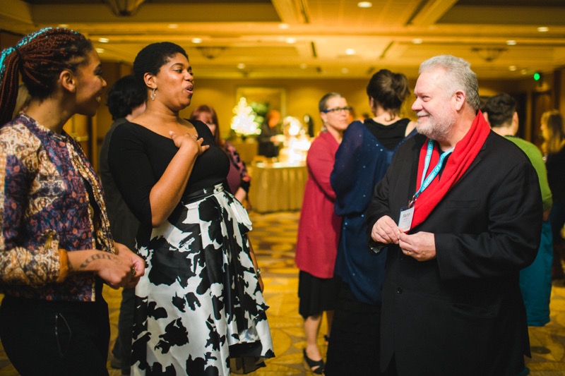 Martin Lammon, founder of the Donald Hall Prize, talks to two guests (Black women dressed in evening attire) at the 2019 AWP Gala