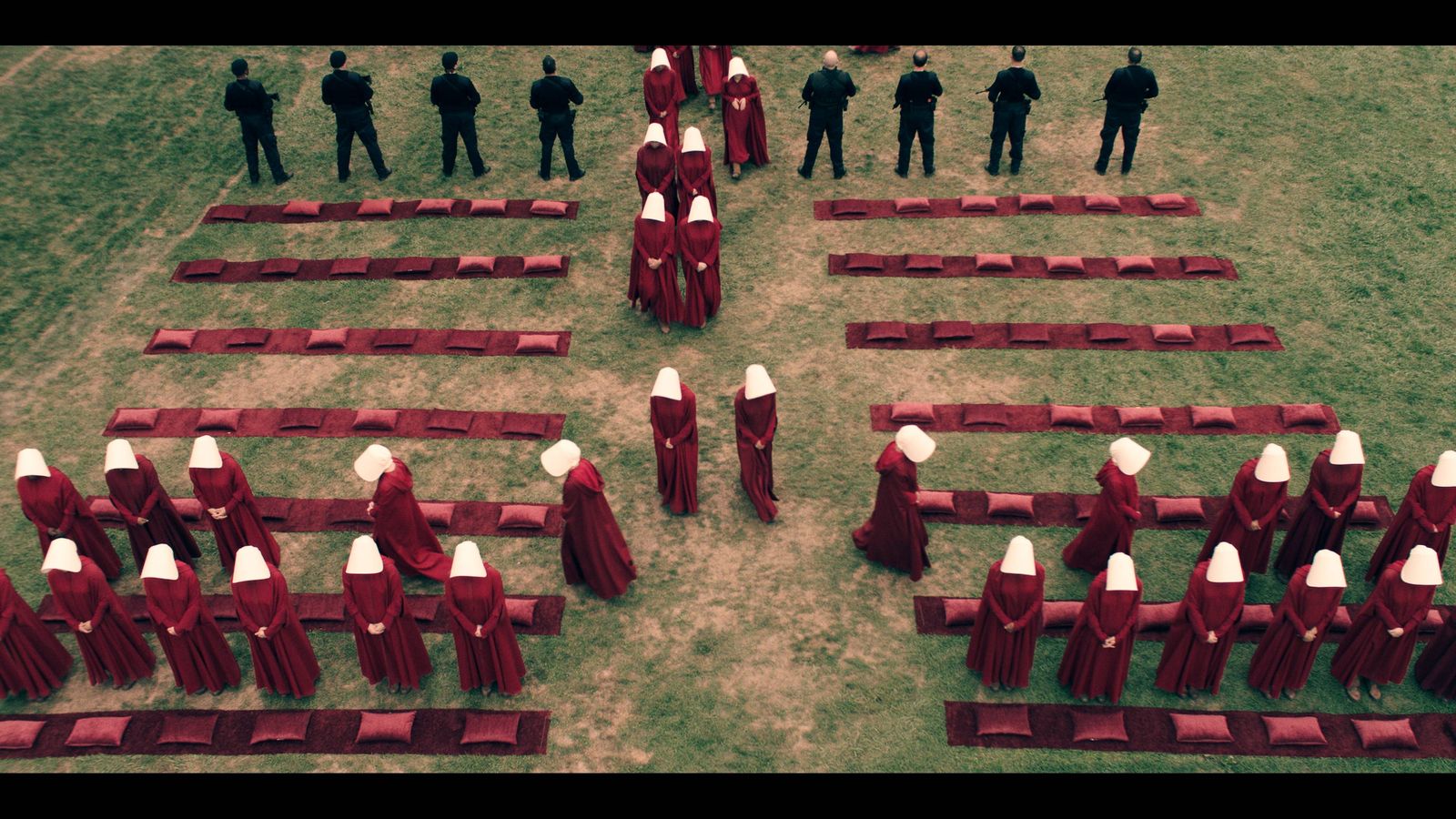 Image of handmaids filing into a grassy area, from the series.